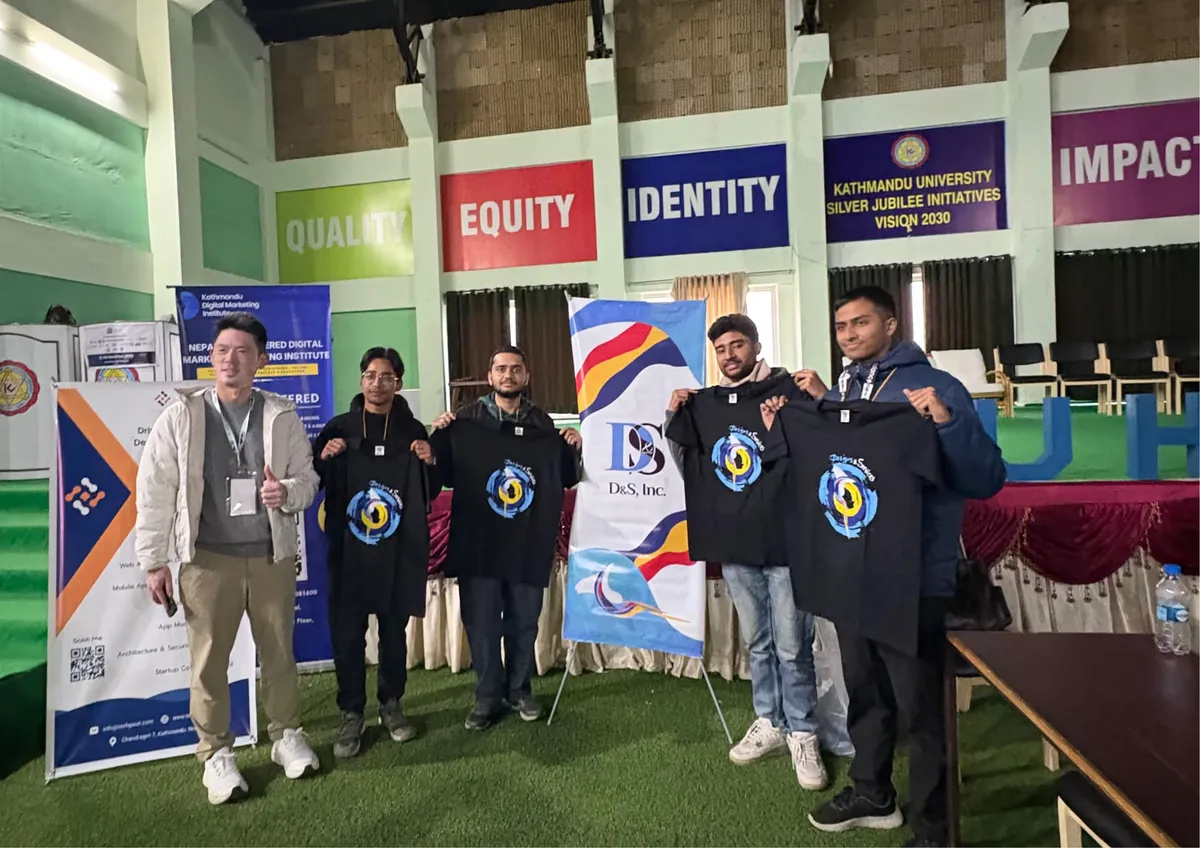 D&S team members on stage at KU Hackfest 2025 holding up branded event t-shirts