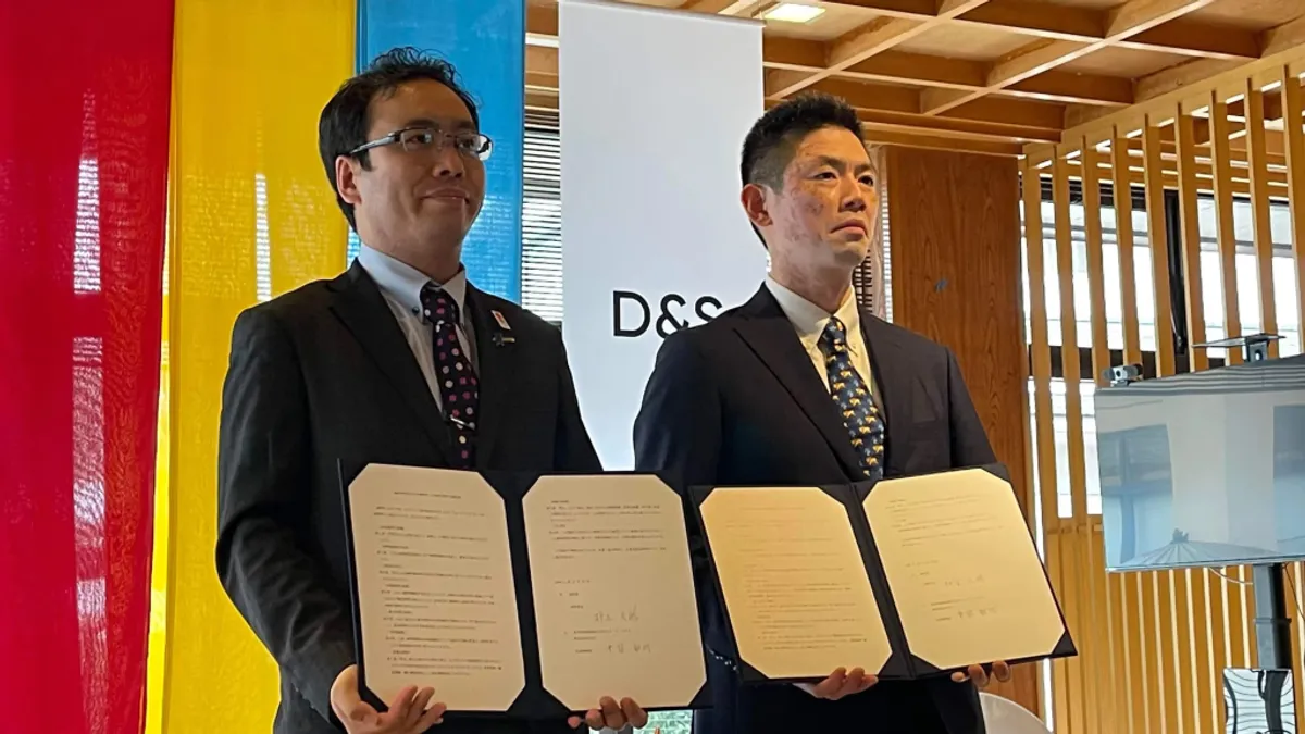 Representatives of D&S and Ureshino City holding the signed collaboration agreement in front of a D&S backdrop